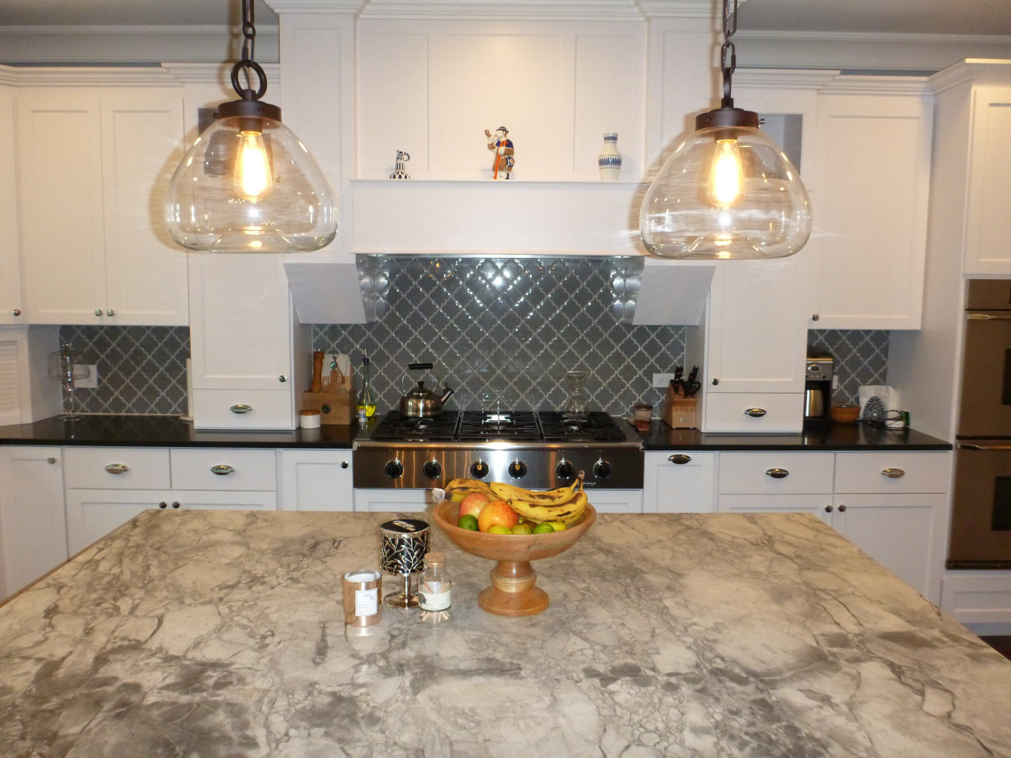 Custom home kitchen design - close up of large island, range/rangehood and glass tile backsplash - Platinum Builders
