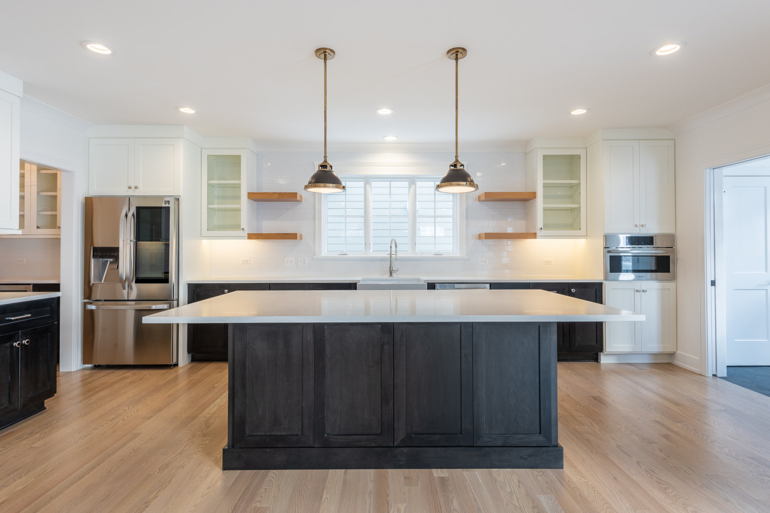 Custom home kitchen design - wide view of island and sink with open shelving above sink - Platinum Builders