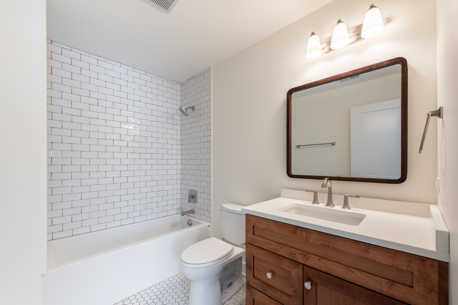 Custom home full bath - second full bathroom with vanity, toilet and bathtub/shower combo. Shower walls have white subway tiles installed.